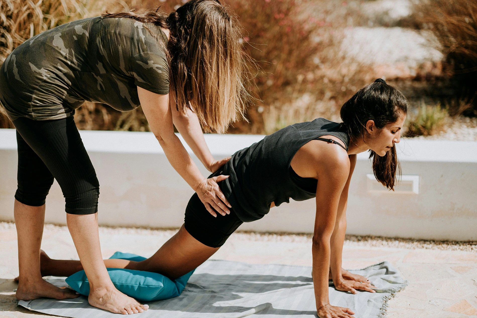Female Personal trainer helping client with form in excercise at home. Wearing black athletic clothes. Female client is in extreme focus.